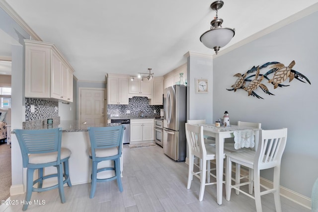 kitchen with backsplash, appliances with stainless steel finishes, stone countertops, a peninsula, and a kitchen breakfast bar