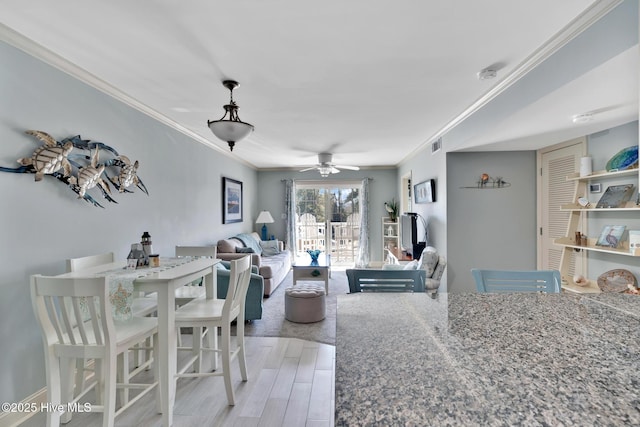 dining room with ceiling fan, light wood finished floors, and crown molding