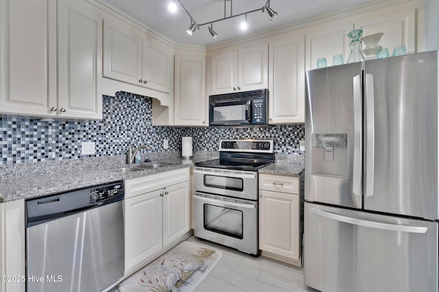 kitchen featuring light stone counters, backsplash, appliances with stainless steel finishes, white cabinets, and a sink