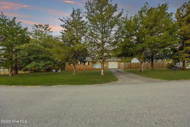 view of front of house featuring driveway, a garage, fence, and a front yard