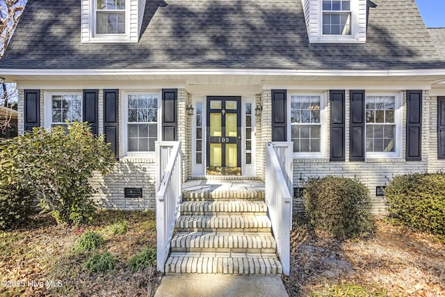 doorway to property featuring roof with shingles, brick siding, and crawl space