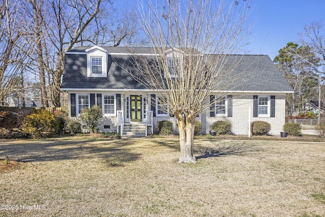 dutch colonial featuring brick siding, roof with shingles, and a front yard