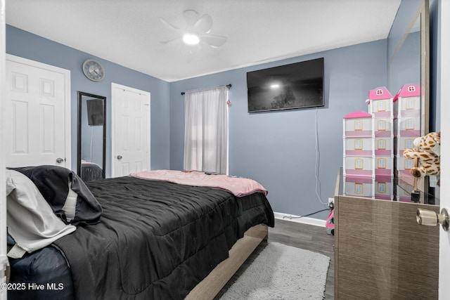 bedroom with dark wood-style flooring, a ceiling fan, and baseboards