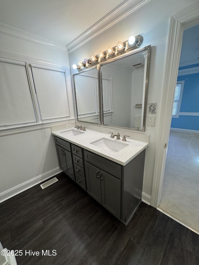 full bathroom with crown molding, visible vents, a sink, and wood finished floors