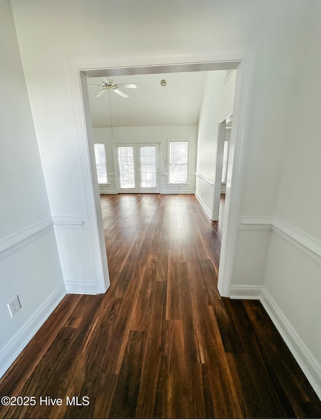 interior space with plenty of natural light, baseboards, vaulted ceiling, and dark wood-type flooring