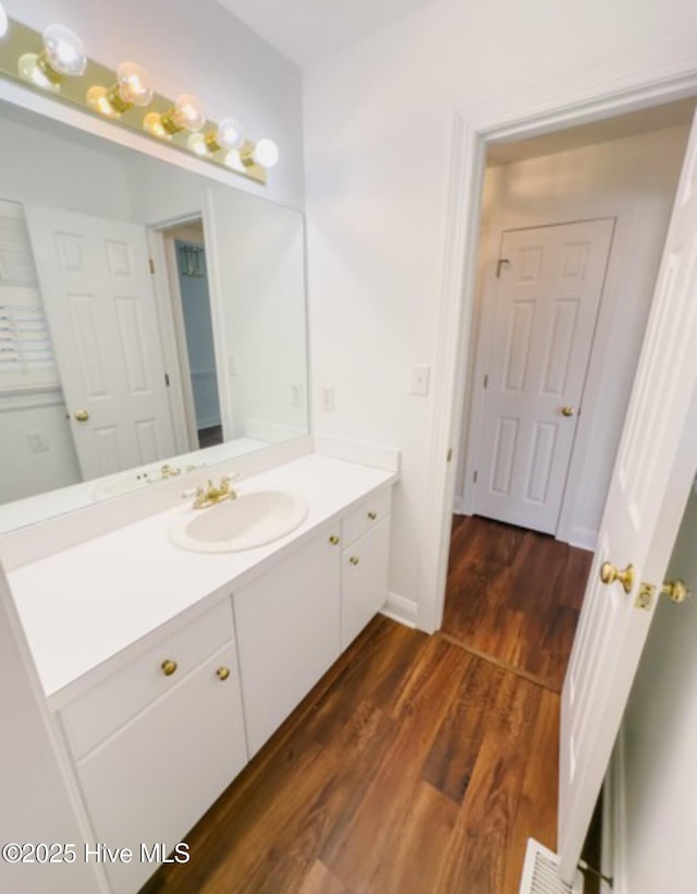 bathroom featuring baseboards, wood finished floors, and vanity