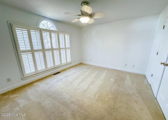 carpeted spare room featuring a ceiling fan, visible vents, and baseboards