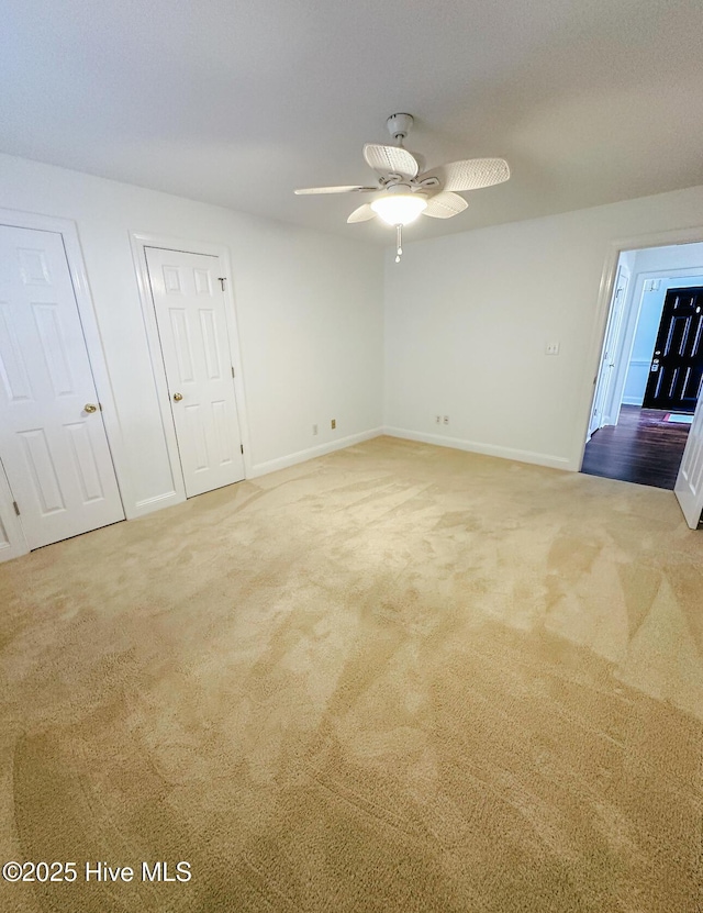 carpeted spare room featuring ceiling fan and baseboards