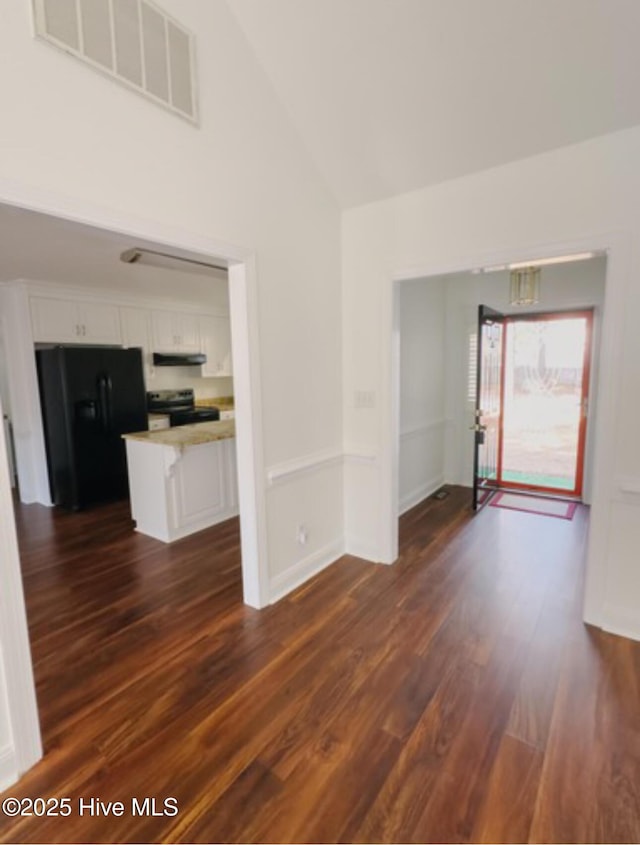 unfurnished living room with high vaulted ceiling, baseboards, visible vents, and dark wood-type flooring