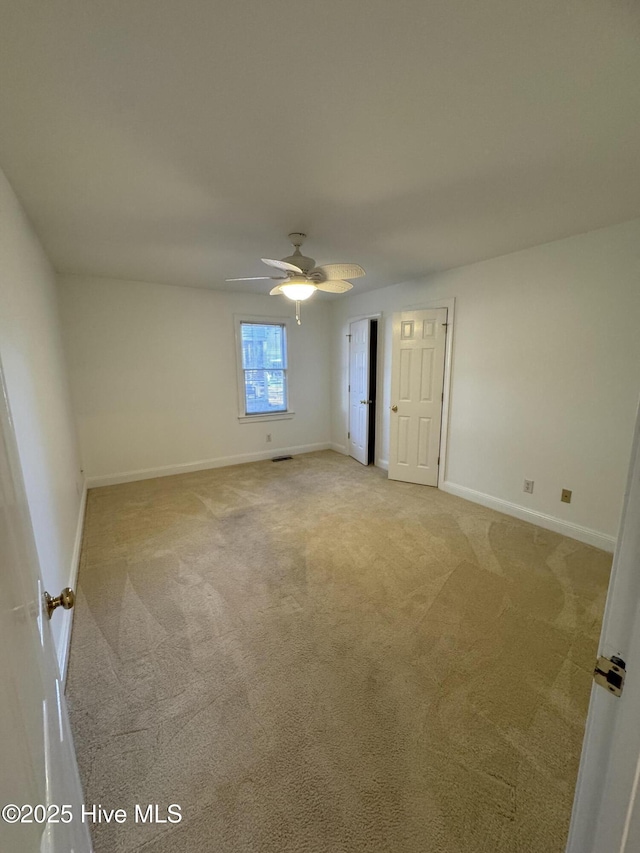 unfurnished room featuring light carpet, baseboards, and a ceiling fan