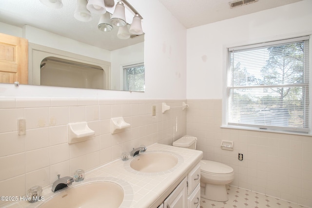 bathroom with toilet, a wealth of natural light, and a sink