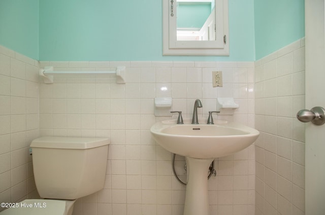 bathroom featuring toilet, tile walls, and wainscoting