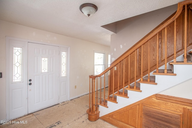 entryway with stairway and a textured ceiling