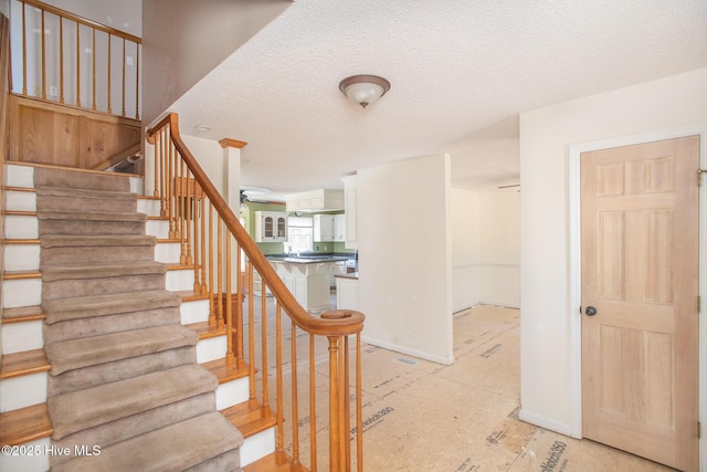 staircase with baseboards and a textured ceiling