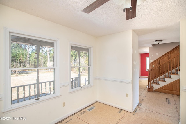 empty room featuring visible vents, baseboards, ceiling fan, stairs, and a textured ceiling