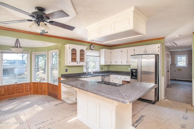 kitchen with a sink, appliances with stainless steel finishes, a textured ceiling, white cabinetry, and crown molding