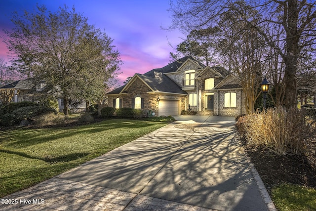 view of front of home featuring an attached garage, concrete driveway, and a yard