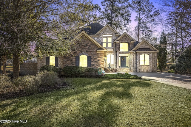 view of front of home with concrete driveway, a yard, and brick siding