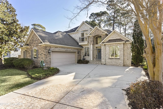 view of front of home with driveway, stone siding, roof with shingles, a front yard, and an attached garage