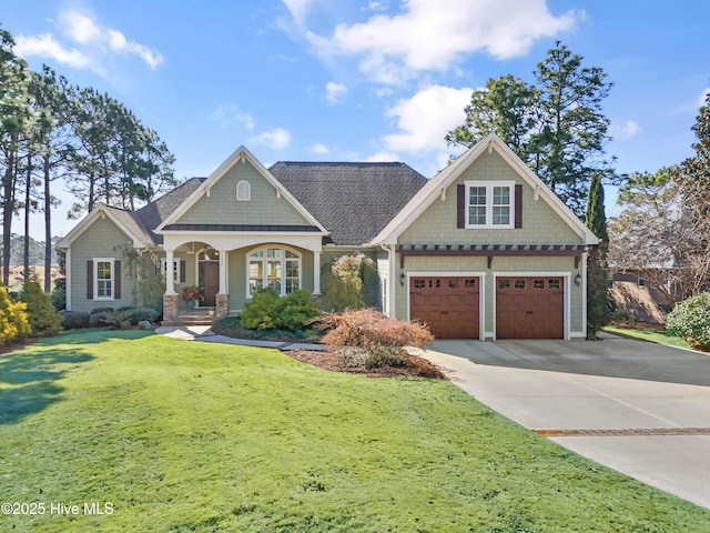 craftsman inspired home featuring driveway, covered porch, a garage, and a front lawn