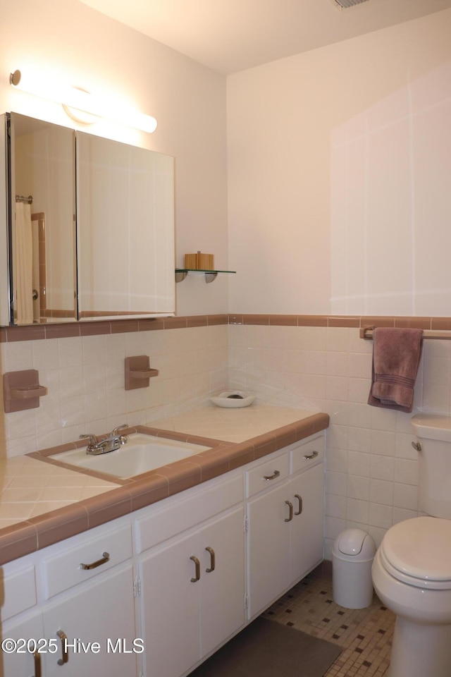 full bathroom featuring a wainscoted wall, tile walls, visible vents, toilet, and vanity