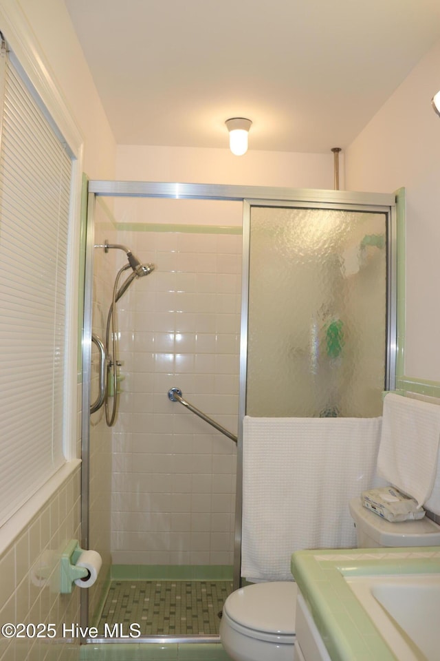 full bathroom with toilet, a shower stall, tile walls, and vanity