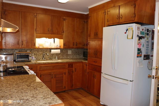 kitchen with decorative backsplash, ornamental molding, freestanding refrigerator, ventilation hood, and a sink