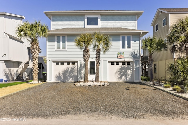 coastal inspired home with stairs, driveway, and an attached garage