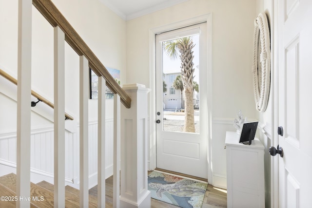 doorway with stairs, ornamental molding, and wood finished floors