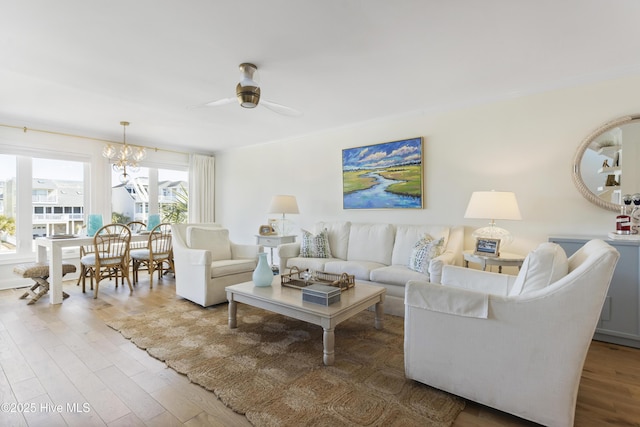 living room with ornamental molding, ceiling fan with notable chandelier, and wood finished floors