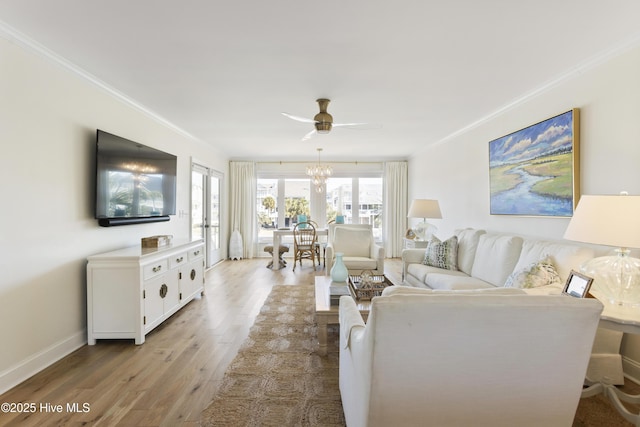 living area featuring baseboards, light wood-type flooring, a ceiling fan, and crown molding