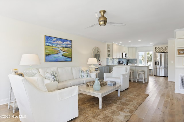 living room featuring baseboards, ceiling fan, crown molding, light wood-style floors, and recessed lighting