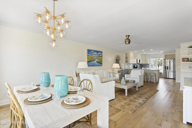 dining room with ceiling fan with notable chandelier, light wood-type flooring, and recessed lighting