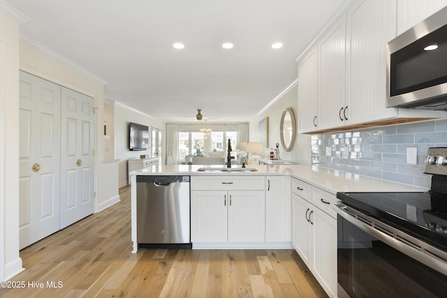 kitchen featuring stainless steel appliances, crown molding, a peninsula, and decorative backsplash