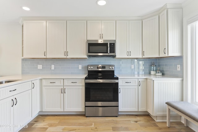 kitchen featuring stainless steel appliances, decorative backsplash, light countertops, and light wood-style floors