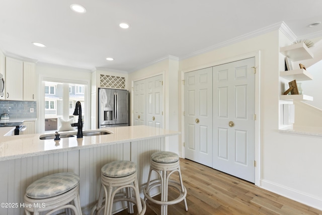 kitchen featuring stainless steel appliances, a breakfast bar, a sink, and ornamental molding