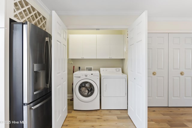 laundry room featuring ornamental molding, light wood-type flooring, cabinet space, and washing machine and clothes dryer