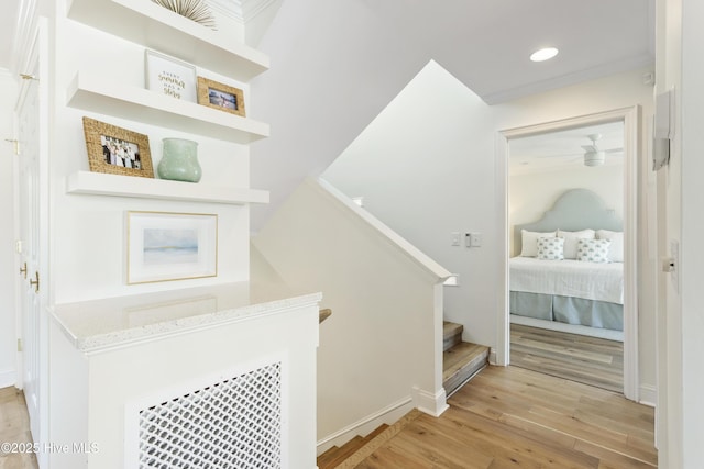 corridor featuring light wood finished floors, stairs, baseboards, and recessed lighting