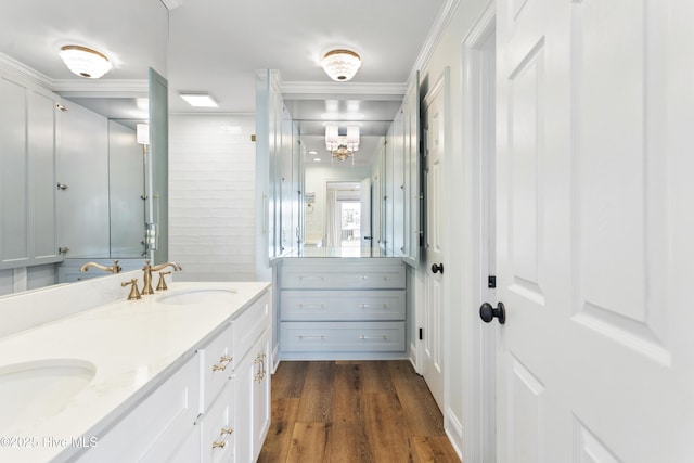 full bath with a sink, double vanity, ornamental molding, and wood finished floors