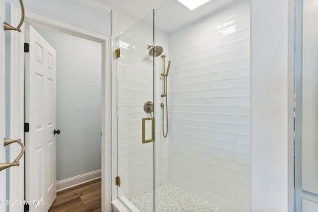 bathroom featuring a stall shower, baseboards, and wood finished floors