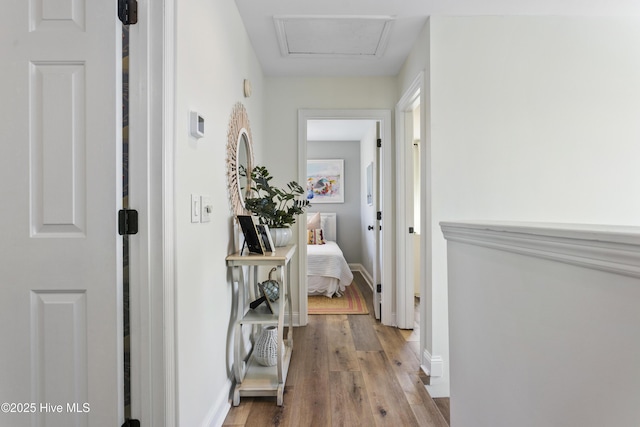 hall featuring attic access, baseboards, and wood finished floors