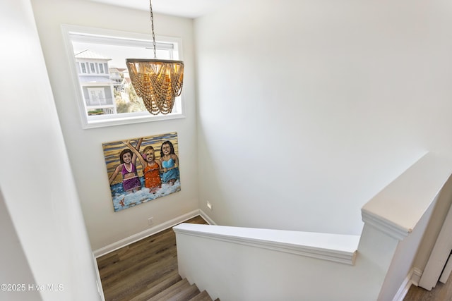 stairway featuring a chandelier, wood finished floors, and baseboards