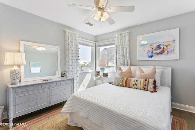 bedroom with dark wood-style floors, visible vents, ceiling fan, and baseboards