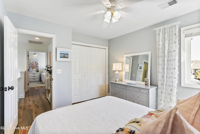 bedroom featuring dark wood-style flooring, a closet, visible vents, and a ceiling fan