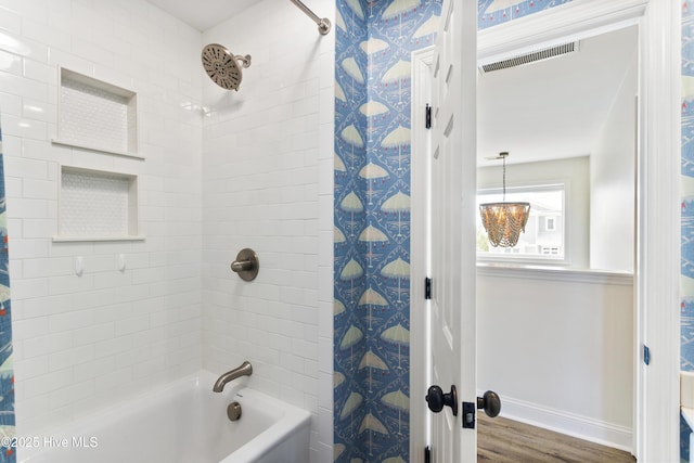 bathroom with shower / bath combo, visible vents, baseboards, and wood finished floors