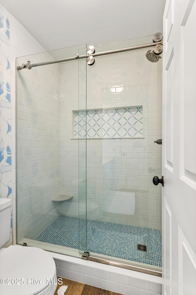 bathroom with toilet, a shower stall, and wood finished floors