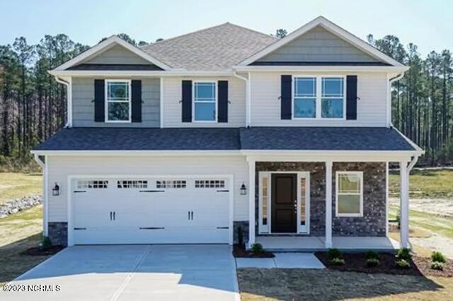 view of front of property featuring covered porch, an attached garage, driveway, and stone siding