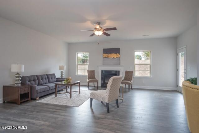 living room featuring baseboards, a ceiling fan, a glass covered fireplace, and wood finished floors
