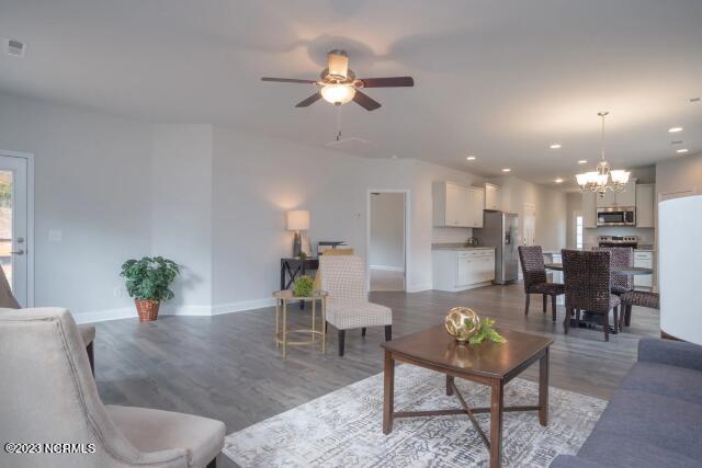 living room with recessed lighting, baseboards, wood finished floors, and ceiling fan with notable chandelier