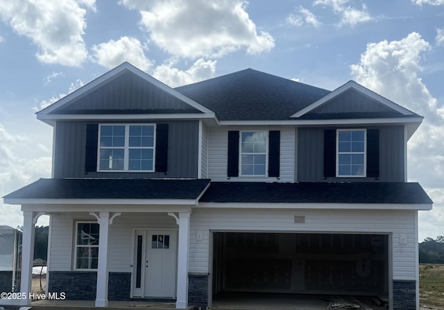 view of front of home with a shingled roof, an attached garage, stone siding, a porch, and driveway